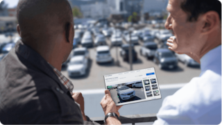 two men talking and watching a tablet