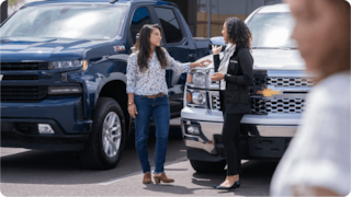 Women talking in front of a car