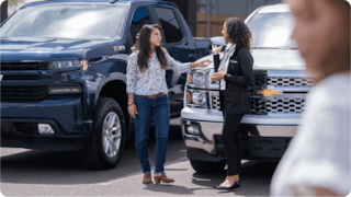 Women talking in front of a car