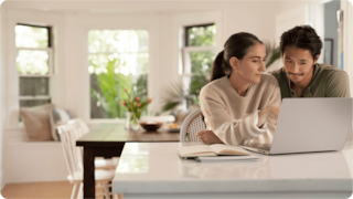 two peolple talking in front of a computer