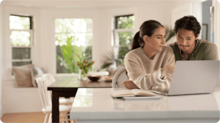two peolple talking in front of a computer