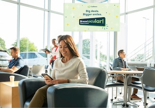 Customers and staff in a bright CarBravo dealership waiting area